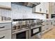 Close-up of a stainless steel gas range with white cabinets and a herringbone tile backsplash at 17300 Pesce Loop, Montverde, FL 34756