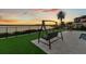 Patio swing overlooking the water at sunset with artificial turf and travertine pavers at 17300 Pesce Loop, Montverde, FL 34756