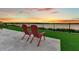 Patio chairs overlooking the water at sunset with artificial turf and travertine pavers at 17300 Pesce Loop, Montverde, FL 34756