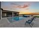 Backyard with an in-ground pool and a screened lanai overlooking the water at sunset at 17300 Pesce Loop, Montverde, FL 34756