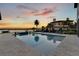 Backyard with an in-ground pool, travertine pavers and lush landscaping overlooking the water at sunset at 17300 Pesce Loop, Montverde, FL 34756