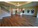 Open-concept living room with wood floors, modern lighting, a staircase, and a kitchen in the background at 2313 Ivy Harvest Pl, Oviedo, FL 32765