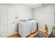 Clean and modern laundry room with washer, dryer, hardwood floors, and white door at 2365 Eagle Trace Dr, Kissimmee, FL 34746
