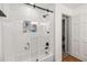 Bright bathtub-shower combo with glass door, white tile, and open shelving at 2365 Eagle Trace Dr, Kissimmee, FL 34746