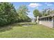 View of the backyard that contains a home, grass, fire pit, trees and surrounding fence at 2502 Falkner Rd, Orlando, FL 32810