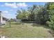 Large grass backyard with a chain link fence, storage shed and lush trees for shade at 2502 Falkner Rd, Orlando, FL 32810
