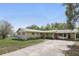 View of the exterior with mature plants, trees, an attached carport and driveway at 2502 Falkner Rd, Orlando, FL 32810
