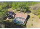 Aerial showcases a screened in pool, and a home with a well-maintained roof surrounded by lush trees and landscaping at 40600 Louise Rd, Umatilla, FL 32784