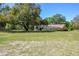 Expansive backyard with screened-in pool and view of the house exterior, surrounded by mature trees at 40600 Louise Rd, Umatilla, FL 32784