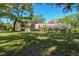 Expansive backyard featuring a screened pool, lush lawn and mature trees on a sunny day at 40600 Louise Rd, Umatilla, FL 32784