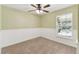 A charming bedroom with carpet, chair rail and a ceiling fan offers a relaxing retreat at 40600 Louise Rd, Umatilla, FL 32784