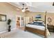 Spacious main bedroom featuring a four-poster bed, ceiling fan and ensuite bathroom access at 40600 Louise Rd, Umatilla, FL 32784