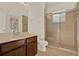 Well-lit bathroom featuring a glass enclosed shower, neutral tile and wood vanity at 4393 S Devon Ct, Kissimmee, FL 34746