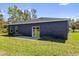 Dark blue house with a sliding glass door and a small patio and green grass at 4761 Sw 142Nd Place Rd, Ocala, FL 34473