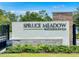 Elegant entrance sign for Spruce Meadow Woodhaven community framed by lush greenery at 6239 Woodhaven Village Dr, Port Orange, FL 32128