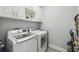 Convenient laundry room featuring white washer and dryer with overhead cabinet storage at 705 Baffie Ave, Winter Park, FL 32789