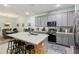 Open kitchen with stainless appliances, gray cabinets, large island with seating that looks into the dining room at 9743 Amber Chestnut Way, Winter Garden, FL 34787