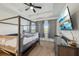A carpeted main bedroom with a dark four-poster bed, a ceiling fan and a mounted TV at 9743 Amber Chestnut Way, Winter Garden, FL 34787
