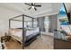 A carpeted main bedroom with a dark four-poster bed, a ceiling fan and a mounted TV at 9743 Amber Chestnut Way, Winter Garden, FL 34787