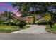 Home featuring mature trees, manicured lawn, and a paved driveway at dusk with glowing illuminated windows at 10116 Pointview Ct, Orlando, FL 32836