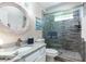 Stylish bathroom with a modern vanity, round mirror, and a glass-enclosed shower with textured tile at 11139 Crooked River Ct, Clermont, FL 34711