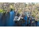 Aerial view of boat on dock on a tranquil lake surrounded by mature cypress trees at 11139 Crooked River Ct, Clermont, FL 34711