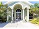 Welcoming front porch with an arched entry and classic columns, complemented by vibrant tropical foliage at 11139 Crooked River Ct, Clermont, FL 34711