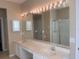 Bathroom featuring a large mirror with vanity lights, double sinks, and a glass-enclosed shower at 13422 Exbury Ln, Windermere, FL 34786