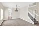 Open-concept living space with carpet, a chandelier, and stairs leading to the second floor at 14740 Hartford Run Dr, Orlando, FL 32828
