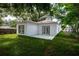 A rear view of the home with a grassy yard, a concrete patio, and large windows and trees at 1505 25Th St, Orlando, FL 32805