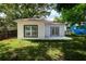 A rear view of the home with a grassy yard, a concrete patio, and large windows at 1505 25Th St, Orlando, FL 32805