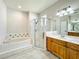 Bright bathroom featuring a soaking tub, glass-enclosed shower, and vanity sink with wood cabinetry at 1913 Lazy Oaks Loop, St Cloud, FL 34771