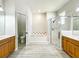 Bright bathroom featuring a soaking tub, glass-enclosed shower, and double vanity sinks with wood cabinetry at 1913 Lazy Oaks Loop, St Cloud, FL 34771