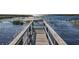 Close-up view of a community wooden boardwalk leading to sparkling water with reflections creating a peaceful waterfront experience at 1913 Lazy Oaks Loop, St Cloud, FL 34771