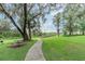 Scenic park pathway leading to a wooden bridge, surrounded by lush greenery and moss-covered trees at 1913 Lazy Oaks Loop, St Cloud, FL 34771