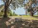 Picturesque waterfront view framed by large trees, complete with a picnic table and a distant pier at 1913 Lazy Oaks Loop, St Cloud, FL 34771