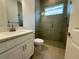 Bathroom featuring a tiled walk-in shower, a single sink vanity, and a linen closet at 2010 Divot Dr, Daytona Beach, FL 32124