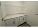 Bright laundry room featuring a stainless steel sink, white cabinets and wire rack at 2013 Divot Dr, Daytona Beach, FL 32124