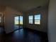 Living room with dark floors, sliding glass doors to backyard, and multiple windows at 2013 Divot Dr, Daytona Beach, FL 32124