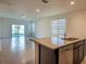 Bright kitchen island with granite countertops and dark cabinets extending to the main living area at 2464 Ribbon Fall Ave, Davenport, FL 33837