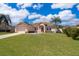 Beautiful one-story home with a lush green lawn, two-car garage, and manicured landscaping on a partly cloudy day at 2712 Pearl Court, Kissimmee, FL 34743