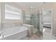 Bright bathroom with a walk-in shower, soaking tub, and light tile surround at 3018 Jardin St, Kissimmee, FL 34741