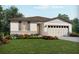 Charming one-story home with a beige exterior, a two car garage, and beautifully landscaped front yard at 309 Castle Dr, Lake Alfred, FL 33850