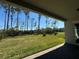 View of the backyard with green lawn and a tree line, as seen from the covered patio at 3108 Firethorn Cir, Daytona Beach, FL 32124