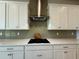 Close-up of modern stovetop and hood with shaker cabinets and subway tile backsplash at 3108 Firethorn Cir, Daytona Beach, FL 32124