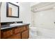 Well-lit bathroom featuring a wooden vanity, black countertop, toilet, and a shower-tub combo with white tiles at 3141 Wainwright St, Deltona, FL 32738