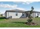 Rear view of a single-story home with a small tree, a well-kept lawn and covered patio at 317 Castle Dr, Lake Alfred, FL 33850