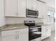 Close-up of the oven, microwave, and granite countertops in a well-equipped, contemporary kitchen at 317 Castle Dr, Lake Alfred, FL 33850