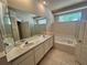 Bright bathroom featuring double sinks, a large mirror, and a relaxing tub with natural light at 450 Dewars Ct, Winter Springs, FL 32708