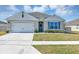 Charming single-story home featuring a two-car garage, well-maintained lawn, and a welcoming front door with wreath at 493 Talisi Loop, St Cloud, FL 34771